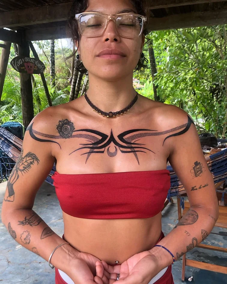 Tatuagem de traços negros orgânicos no peito e nos braços